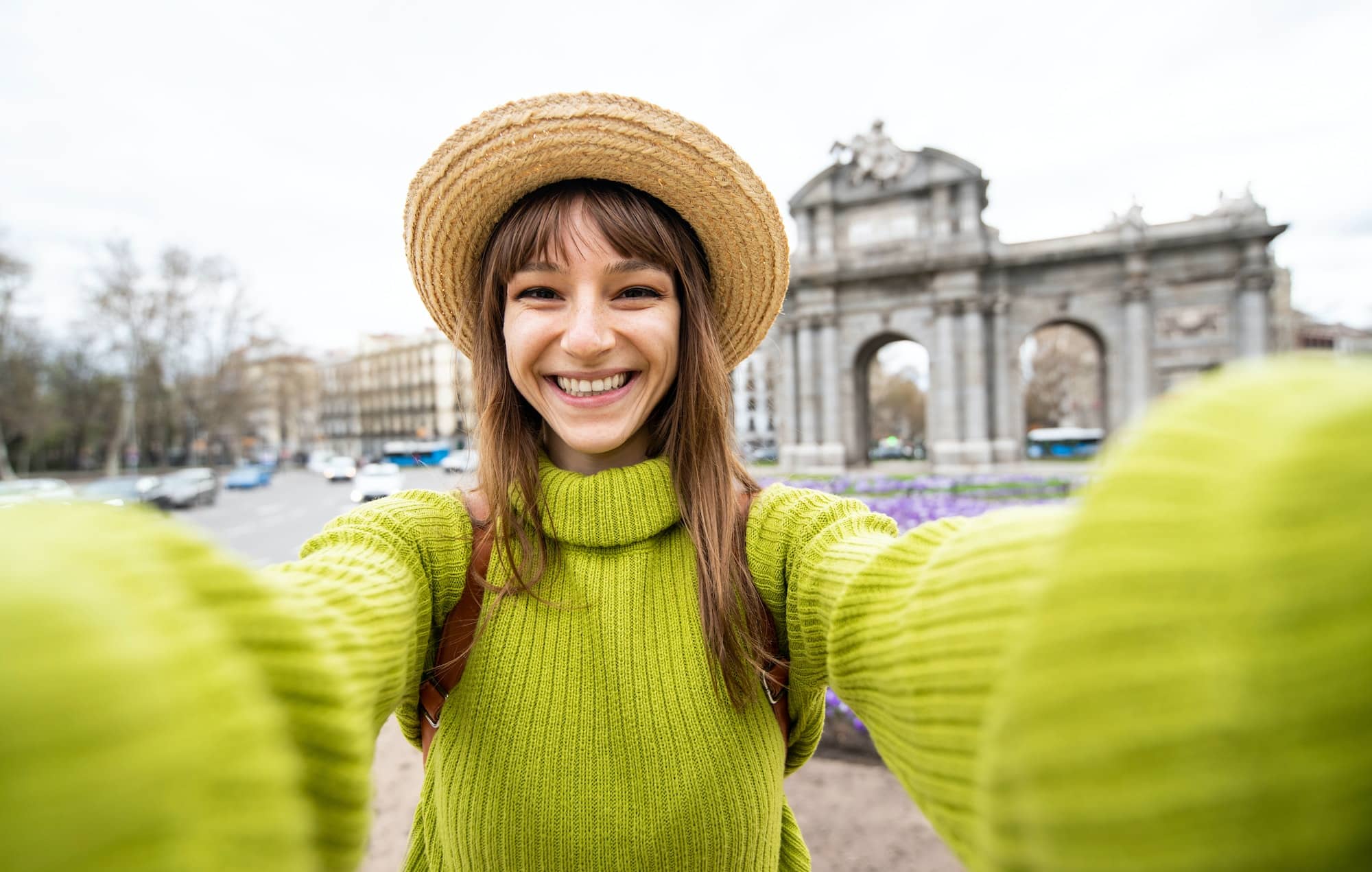 Beautiful female tourist taking selfie at Puerta de Alcala in Madrid, Spain