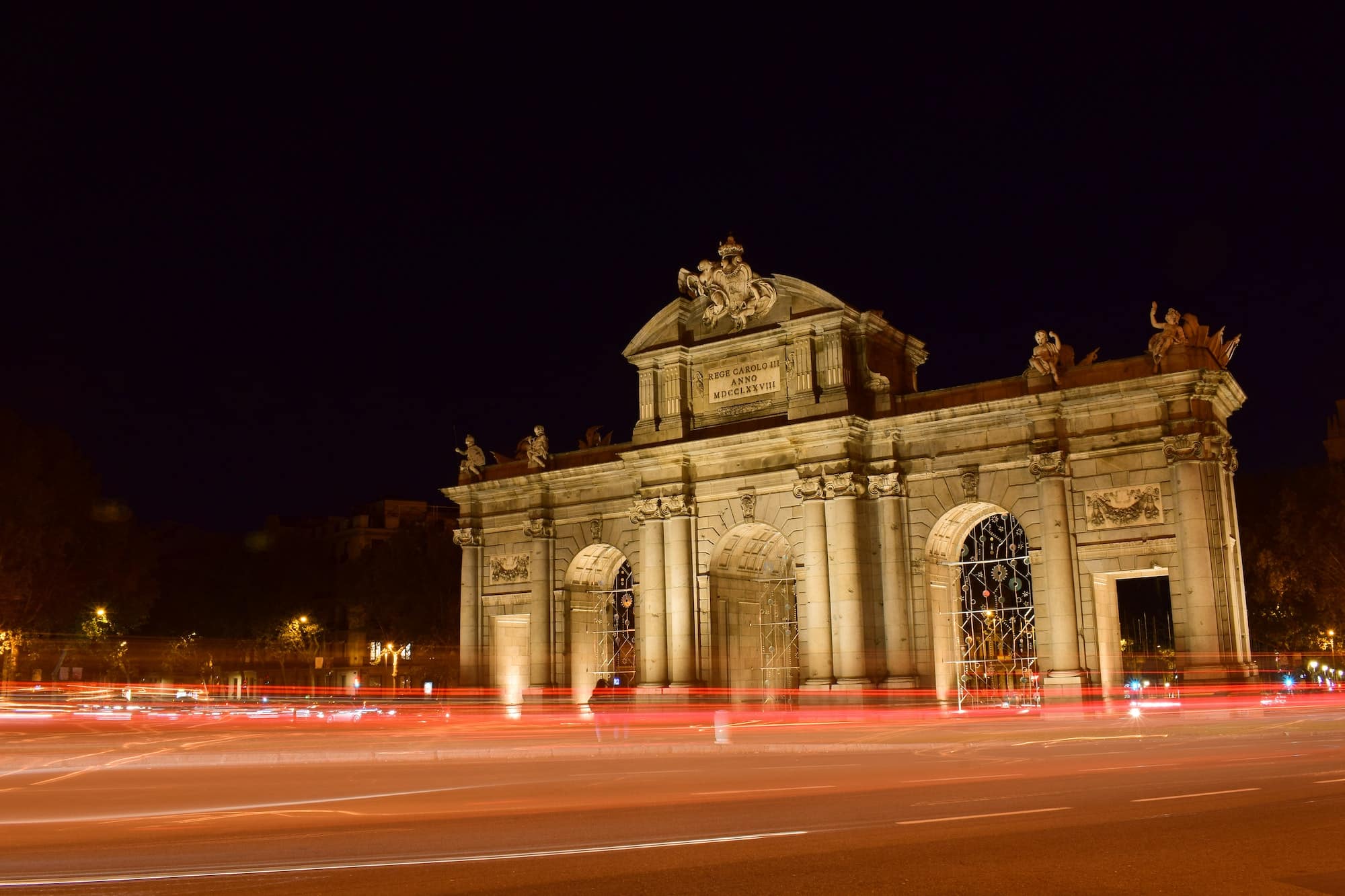 The Puerta de Alcala in Madrid at night. With flashes and lights of cars passing by.