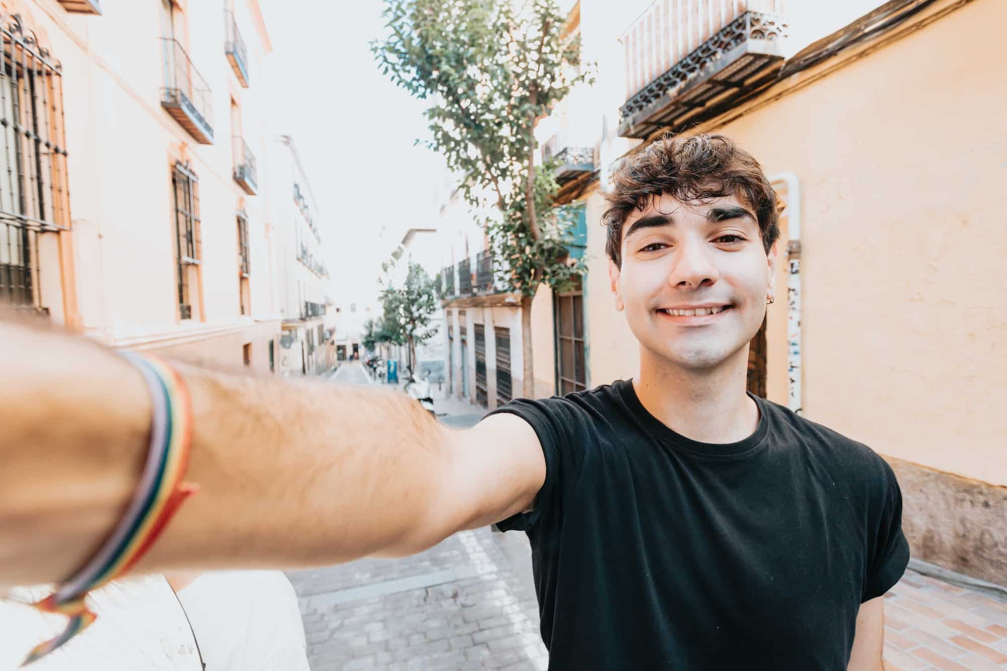 Young man taking a selfie smiling to camera in in the city of madrid with modern styling
